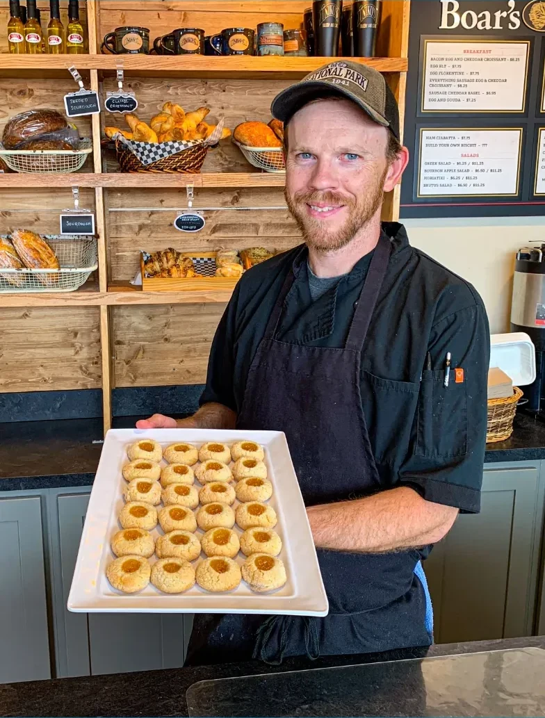 Matt Weafer holding a tray of fresh thumbprint cookies in front of the bread wall