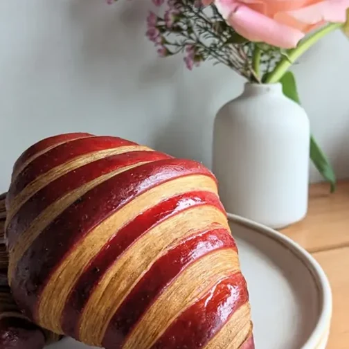 A strawberry-striped croissant on a cafe plate